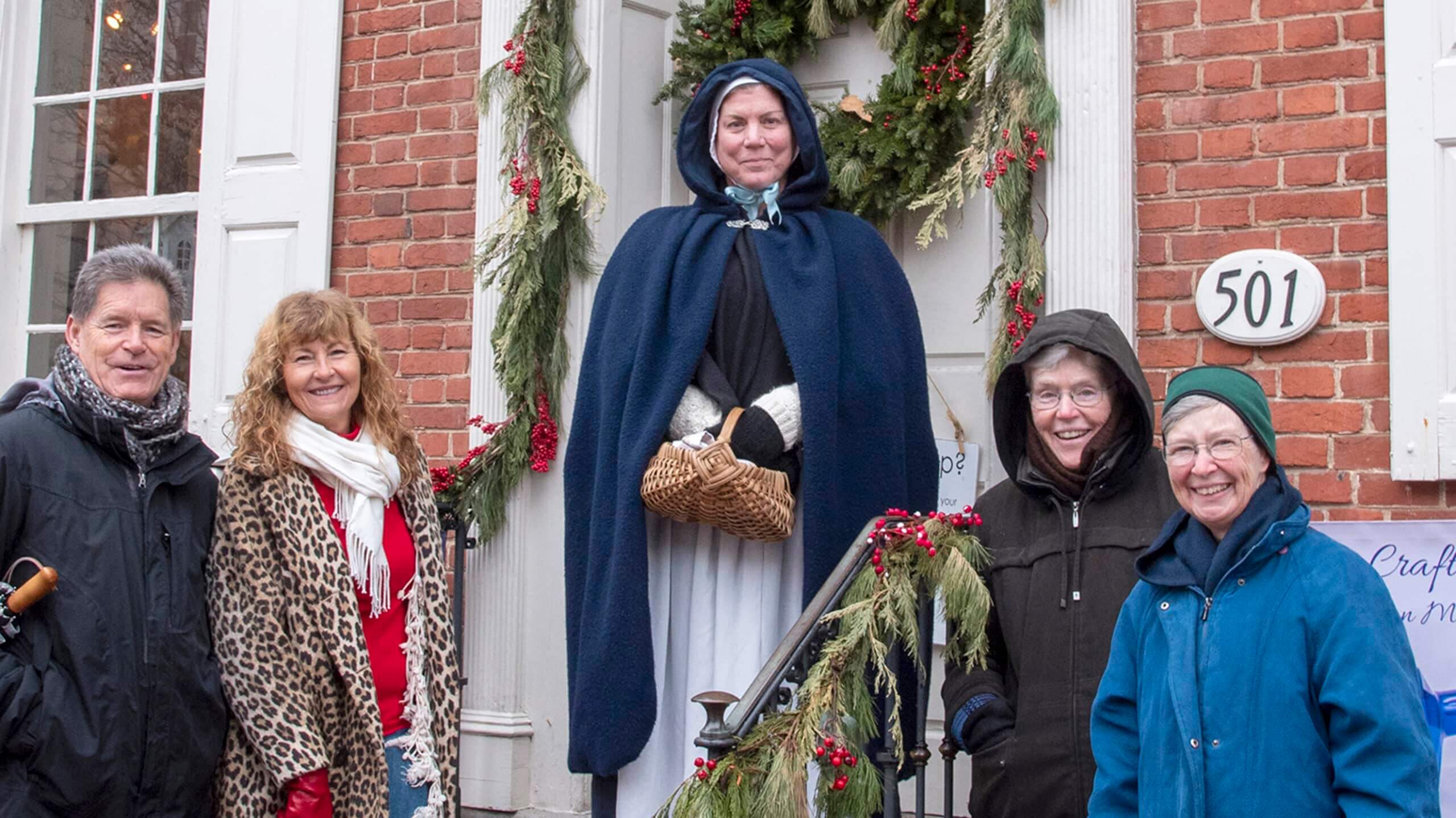 Guests smiling with their docent in front of the Goundie House during Christmas time