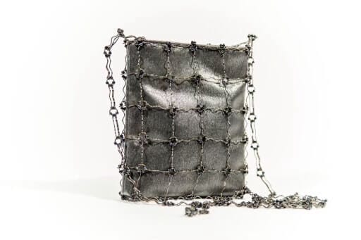 A gray, square purse with silver chains