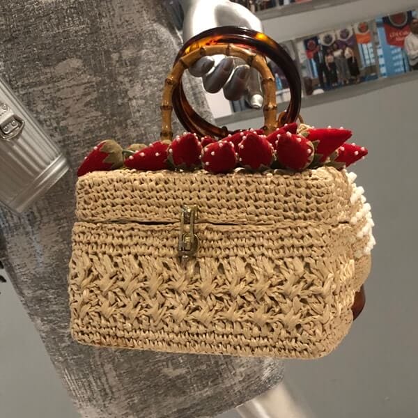 A wicker basket purse with fabric strawberries on top from PURSEonality