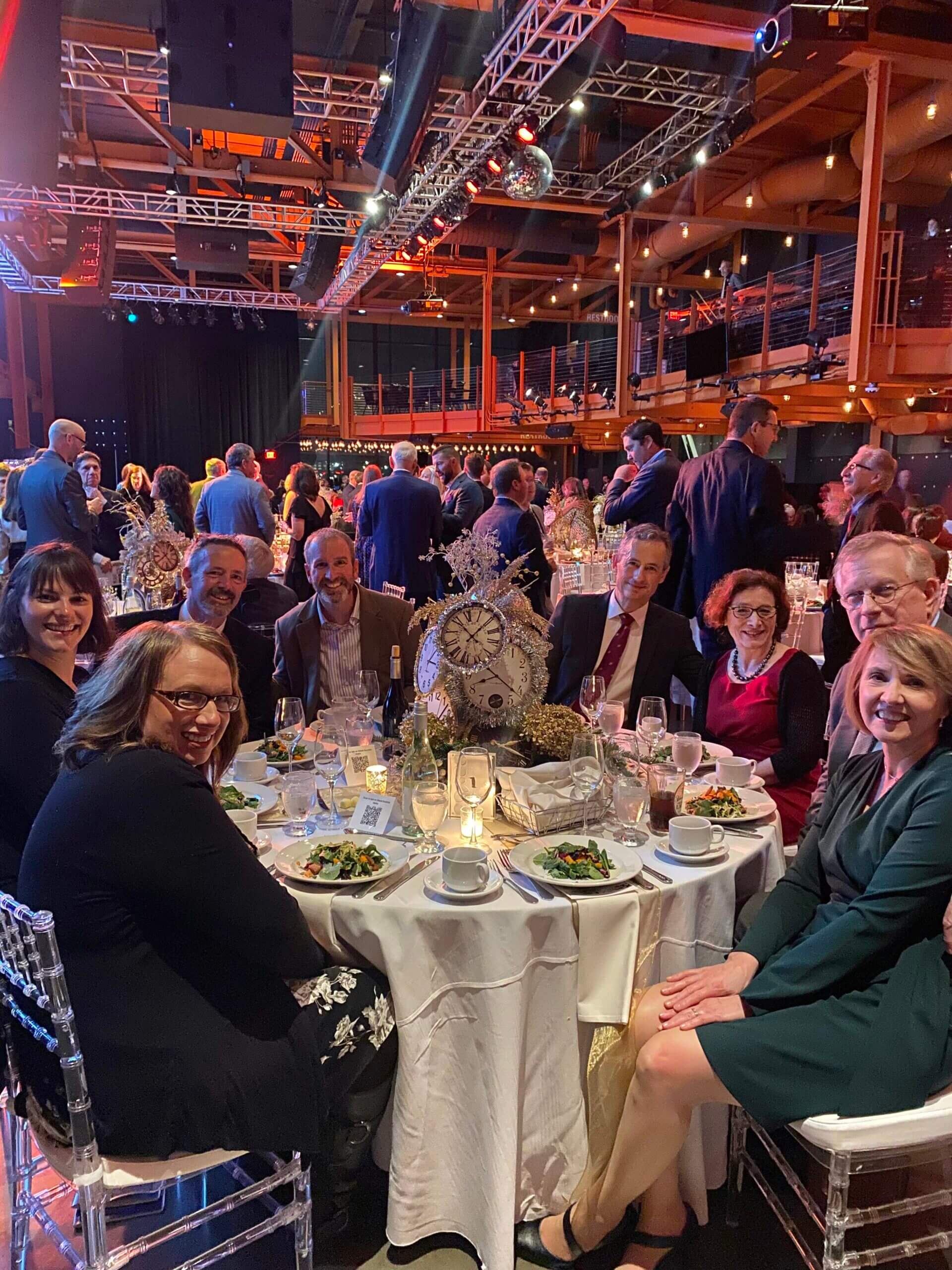 Guests sitting around a table enjoying the Holiday Dinner & Auction