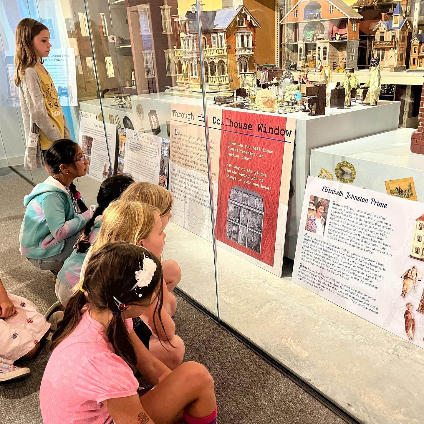 Group of kids observing tiny model homes at exhibition.