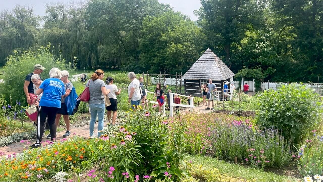 a group of people walking in a garden at historic burnside farm