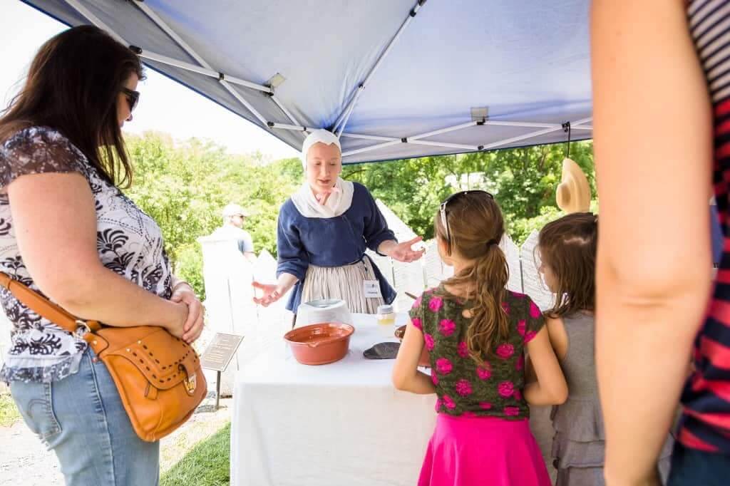 a woman standing in front of a table with people around it at historic burnside farm