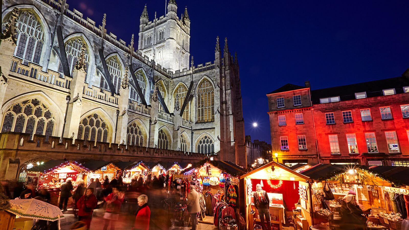 Christmas Market illuminated at night behind Bath Abbey in Somerset